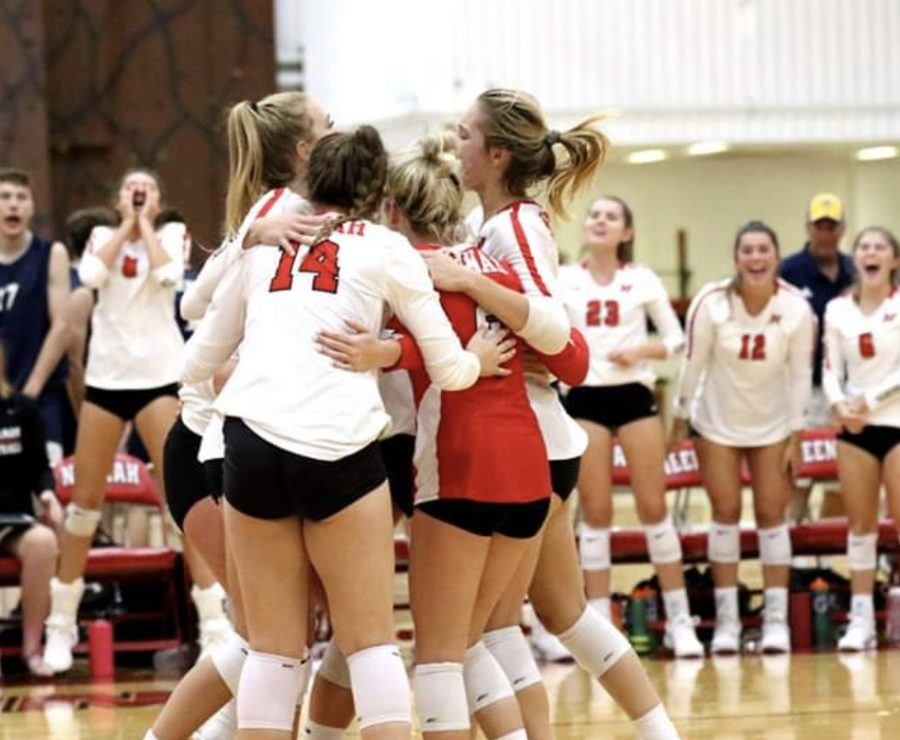 Members of the volleyball  team huddle in support and celebration.