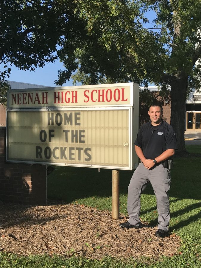 School+Resource+Officer+Nathan+Franzke+in+front+of+the+sign+outside+of+Pickard+Auditorium+at+Neenah+High+School.+