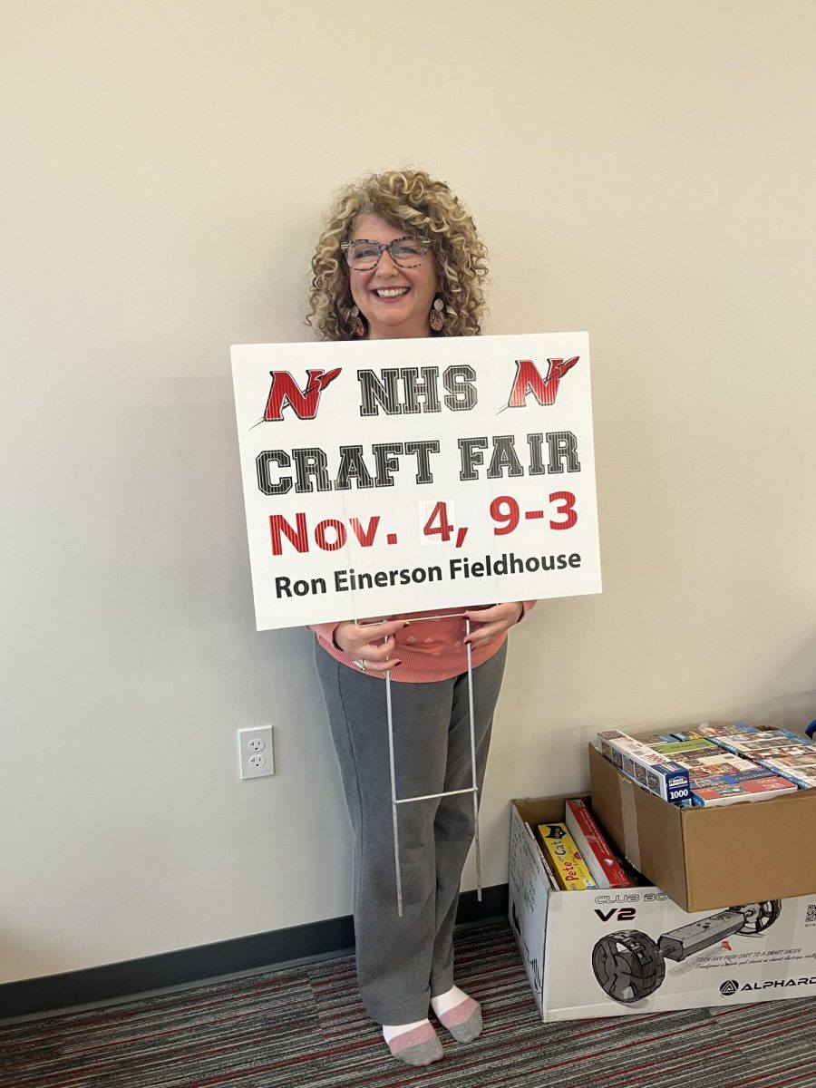 Mrs. Aaholm holding a yard sign made to promote the craft fair.